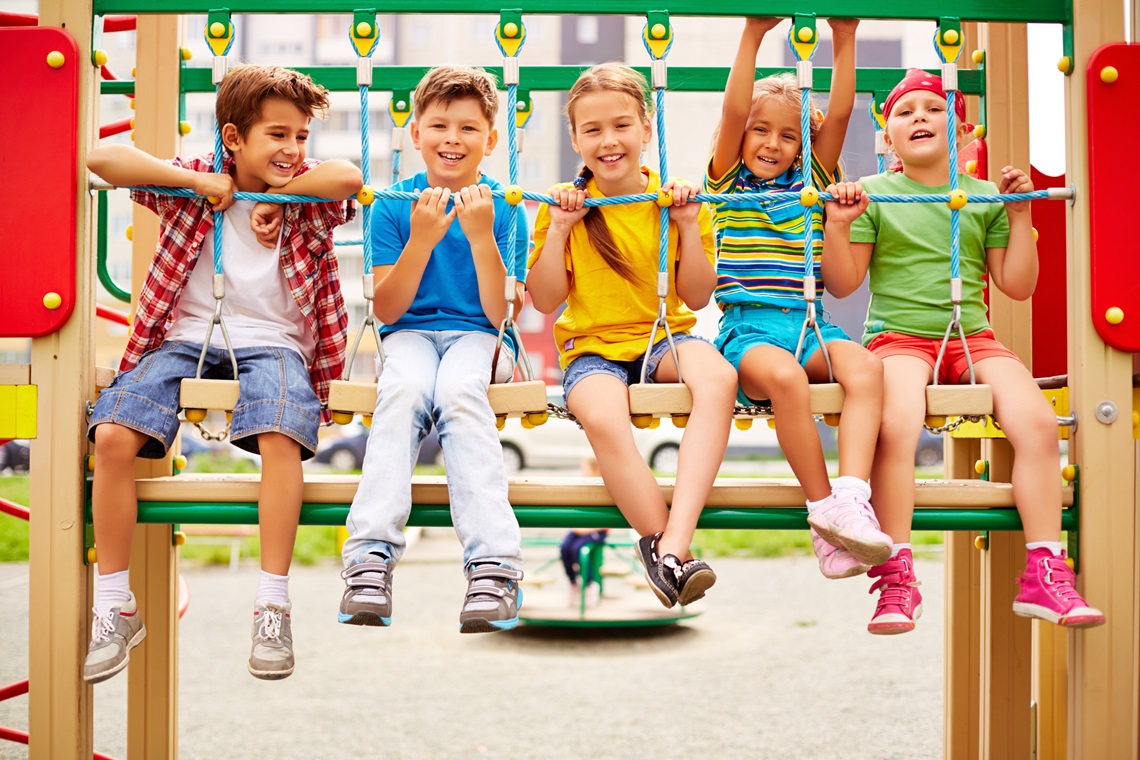 Happy friends sitting on swing and looking at camera